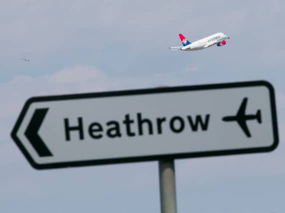A view of a road sign for Heathrow, with a plane taking off in the background