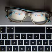 A pair of glasses on a laptop keyboard reflecting the Google logo