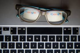 A pair of glasses on a laptop keyboard reflecting the Google logo