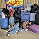 A passenger sleeps on the floor surrounded by luggage at Gatwick Airport in Crawley,