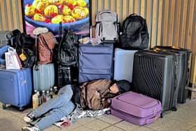 A passenger sleeps on the floor surrounded by luggage at Gatwick Airport in Crawley,