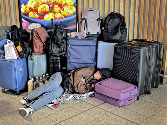 A passenger sleeps on the floor surrounded by luggage at Gatwick Airport in Crawley,