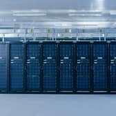 A man pushing a cart beside a row of large servers