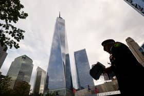 A New York Police Department officer holds US flags next to the reflecting pools at the memorial
