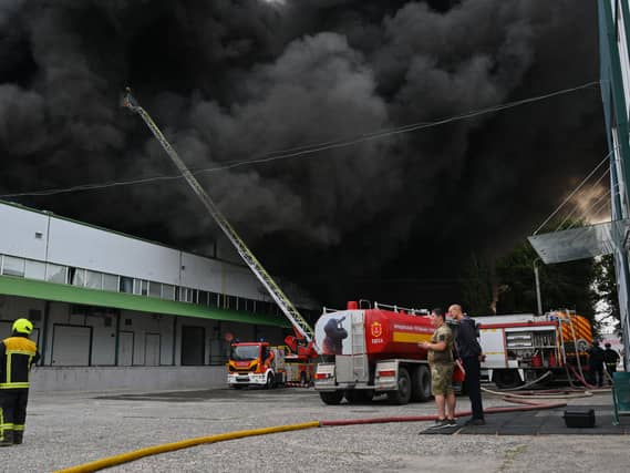 Firefighters tackle a blaze, with a huge cloud of black smoke overhead