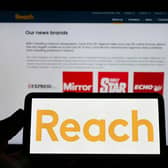 The Reach logo displayed on a smartphone in front of the business webpage