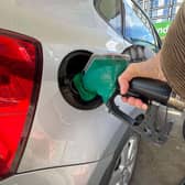 A woman putting putting unleaded petrol into her car at a petrol station in London