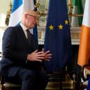 John Swinney and Catherine Connolly talking to each other, seated in front of Irish, Scottish and EU flags