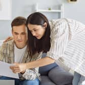 A couple looking at a bill, while on the sofa