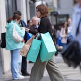 A woman walking on a high street carrying several shopping bags
