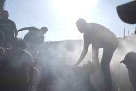 People near a destroyed vehicle following an Israeli air strike in Gaza city