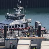 Migrants disembark a boat in a harbour