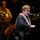 Elton John playing a piano and singing into a microphone