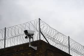 View of barbed wire and a CCTV camera on top of a high wall