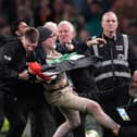 A protester is escorted off the field
