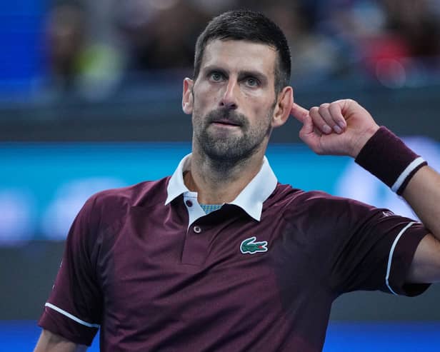 Novak Djokovic holds his finger to his ear