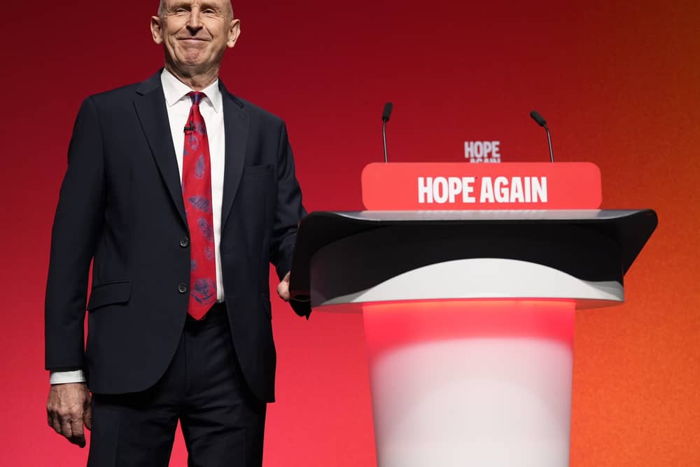 John Healey at the side of a lectern at the Labour Party conference