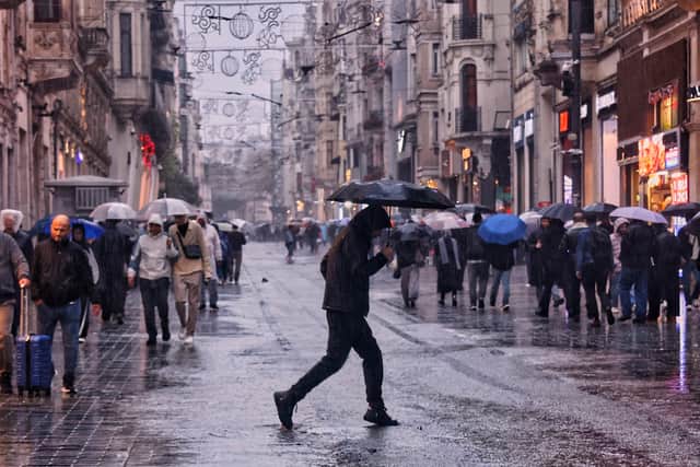 Pedestrians walk along Istiklal main street under heavy rain in Istanbul  (Huseyin Ozdemir/DIA Photo via AP)