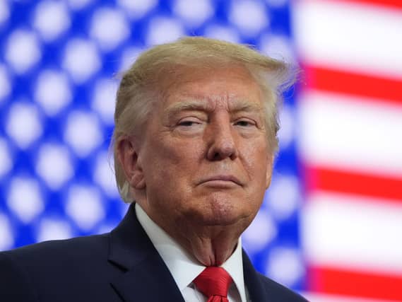 President Donald Trump listens at a campaign rally with the US flag in the background