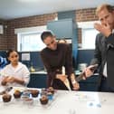 Harry licks icing from his hand as he and the Meghan decorate birthday cupcakes during a visit to Epic Partners in Nottingham
