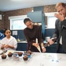Harry licks icing from his hand as he and the Meghan decorate birthday cupcakes during a visit to Epic Partners in Nottingham