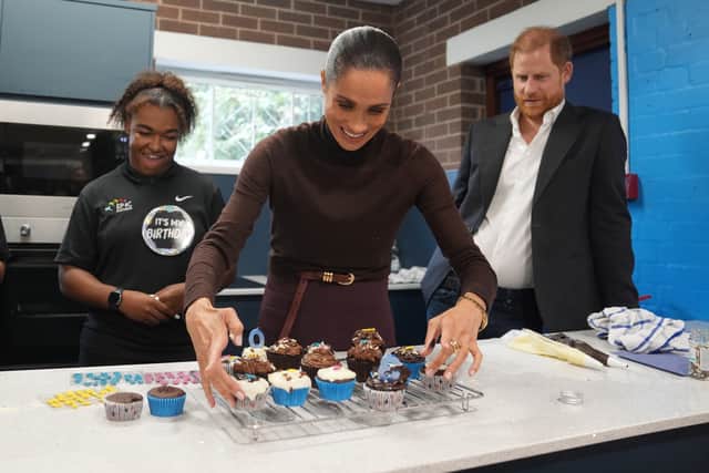 The Duke of Sussex watches as the Duchess of Sussex arranges birthday cupcakes during a visit to Epic Partners in Nottingham (Joe Giddens/PA)
