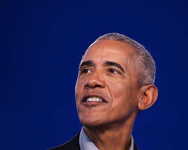 Barack Obama smiling in front of a blue background