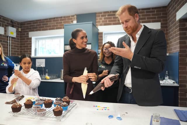 The Duke licks icing from his hand as he and the Duchess of Sussex decorate birthday cupcakes during a visit to Epic Partners in Nottingham (Joe Giddens/PA)