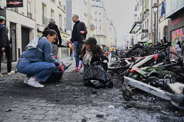People clean up debris in a street next to burned bicycles in the capital (Emma Da Silva/AP)
