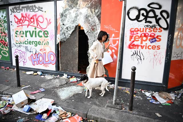 A woman walks her dog past a looted store (Emma Da Silva/AP)