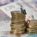 Models of a man and woman standing on a pile of coins and bank notes