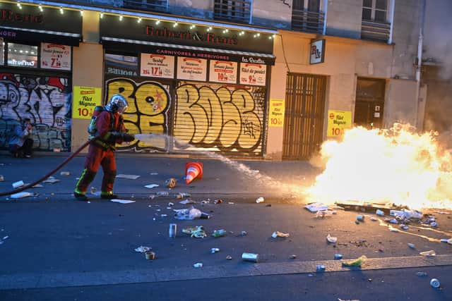 A firefighter extinguishes a blaze during clashes in Paris on Sunday (Emma Da Silva/AP)