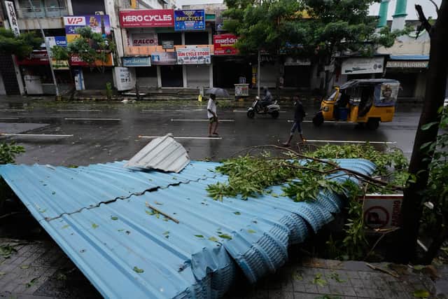 People walk past the destruction caused by Cyclone Arnab (Mahesh Kumar A/AP)