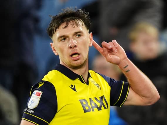 Oxford's Mark Harris puts a finger to his ear to hear the crowd's reaction as he celebrates a goal