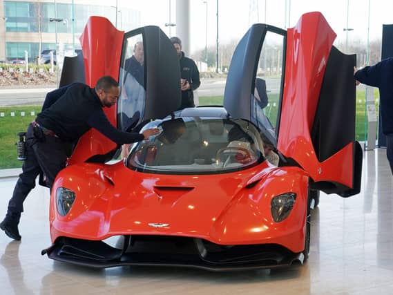 A man polishing a red Aston Martin Valhalla