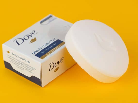 A bar of Dove soap shot on a yellow background along with the product's box packaging