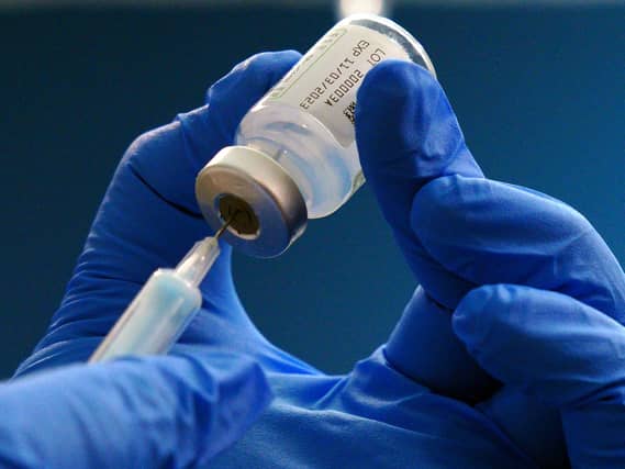 Gloved hands holding vaccine bottle and needle