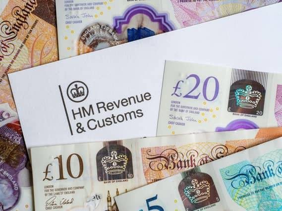 An income tax letter from HM Revenue and Customs among a pile of pound notes