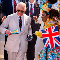 Charles shakes maracas and joins dancers in carnival parade
