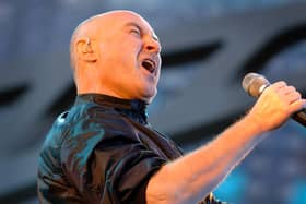 Phil Collins singing into a microphone on stage
