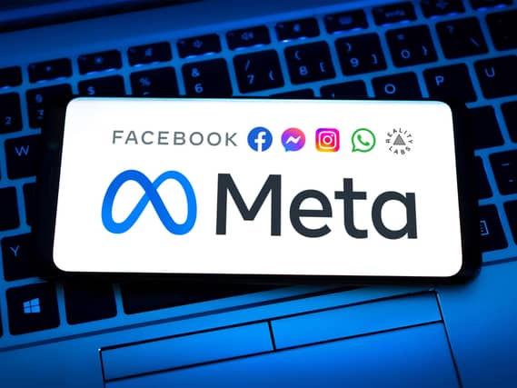 Meta Platforms logo displayed on a mobile device which is on top of a laptop keyboard