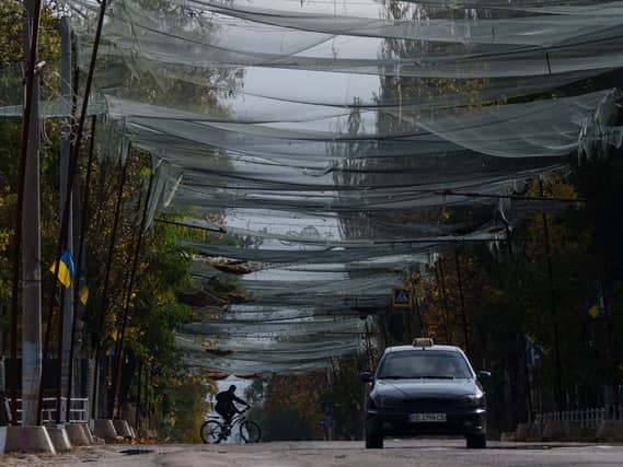 A local man rides a bicycle beneath anti-drone nets stretched over a street during a local ceasefire in Oleshky