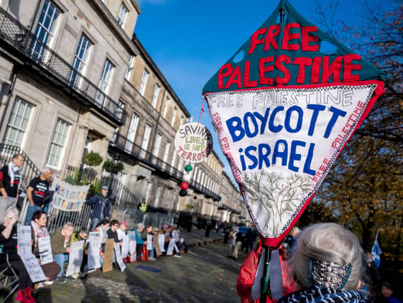 Protestes holding a placard that reads Free Palestine, Boycott Israel