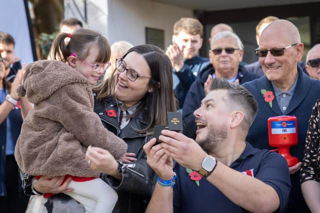 Sergeant Cameron Lewis, 25, RAF, Air Traffic Controller based at RAF Odiham presents a poppy to Neil Fellingham, RAF veteran and Team UK Invictus Games 2025 alumnus, his wife, Lauren, their daughter Poppy, 5