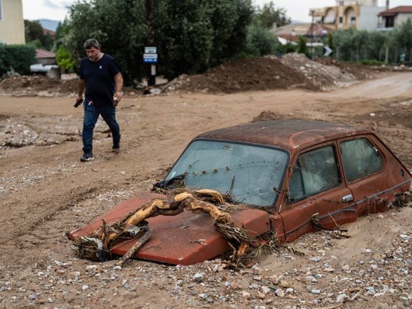 A man walks next to a damaged car after floods in the town of Agria near the city of Volos, Greece