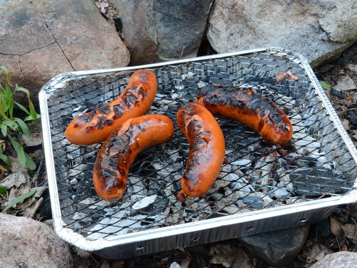 Sausages cooking on a disposable barbecue