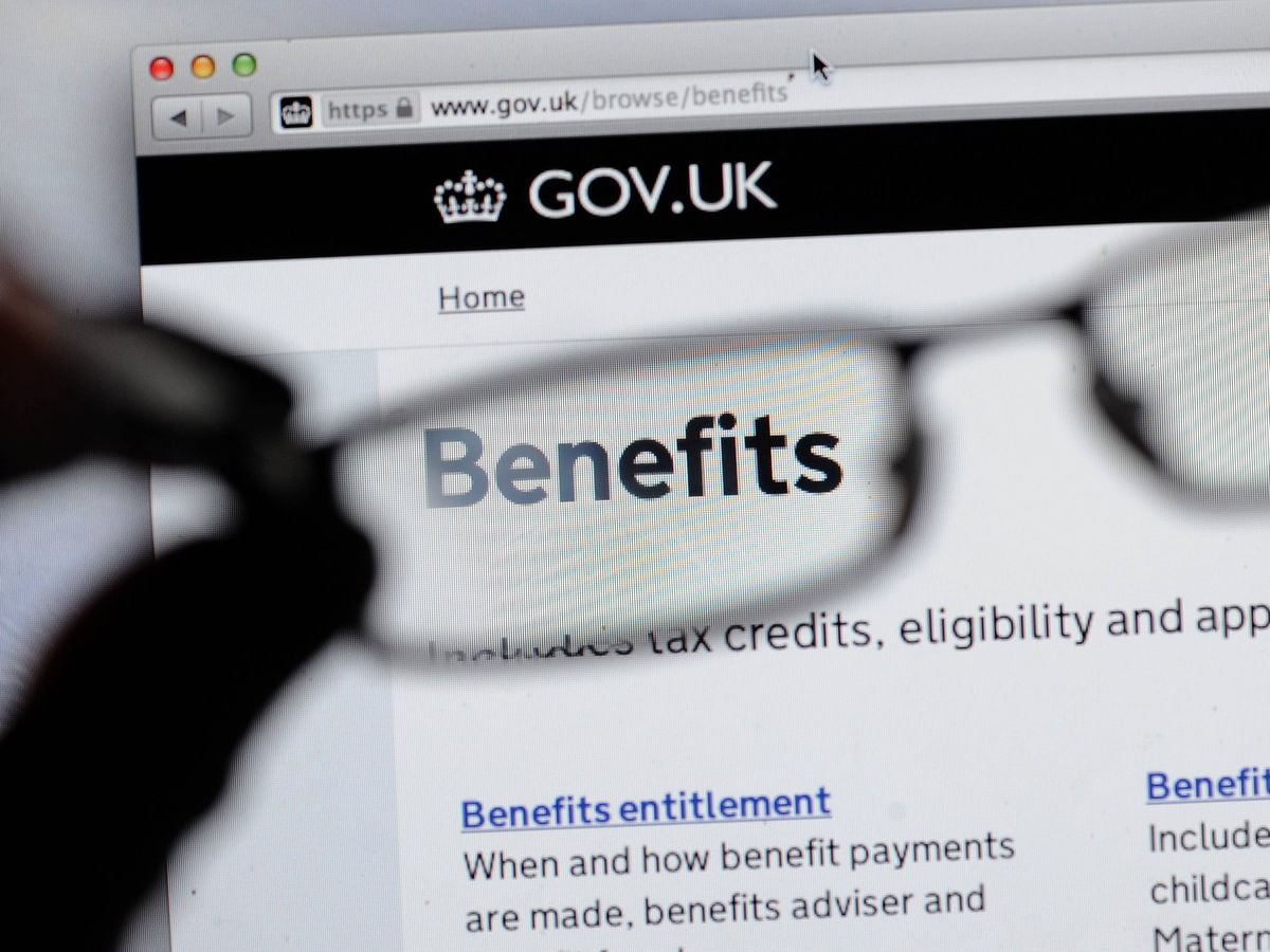 A hand holding glasses in front of the gov.uk website