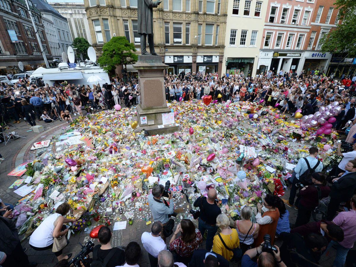 Crowds look at the floral tributes after a minuteâs silence in St Annâs Square, Manchester, to remember the victims of the terror attack in 2017