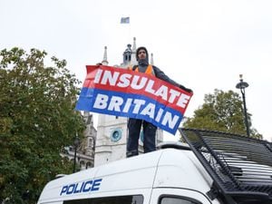 A protester from Insulate Britain stands on a police van