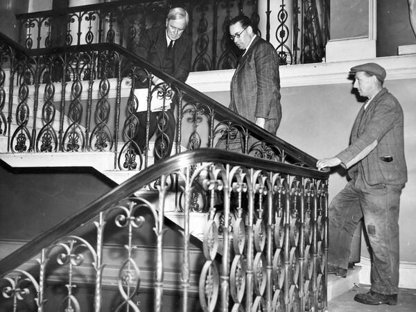 The fine wrought iron staircase. From left, Mr H G Warren, his assistant Mr C E Scanlon, and estate worker Edwin Jones.